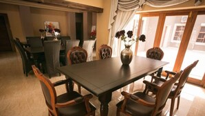 Un comedor con una mesa rectangular rodeada por seis sillas de madera con asientos acolchados. Un jarrón con flores está sobre la mesa.