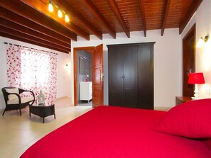 A bedroom with a large bed, a wooden ceiling, a wardrobe, a nightstand with a lamp, and a chair. - Exclusive Villa Margarita with private pool in Puerto del Carmen- Los Mojones (Puerto del Carmen)