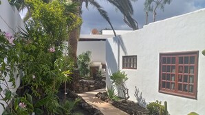 A pathway leading to a white building with a window and a door.