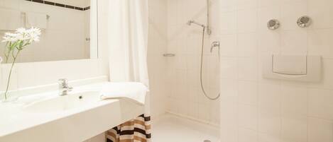 A bathroom with a sink, mirror, shower, and toilet.