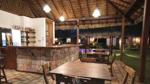An outdoor bar area with wooden furniture and a thatched roof. - Atins Charme Chales (Barreirinhas)