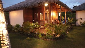 A wooden bungalow with a thatched roof, surrounded by lush tropical plants. - Atins Charme Chales (Barreirinhas)