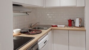 A modern kitchen with white cabinets, a stainless steel sink, a stove, and a dishwasher.