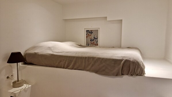 A minimalist room with a bed, a lamp, and a framed picture on the wall. - Central charming Apt South butte Montmartre up to 7 people (Paris)