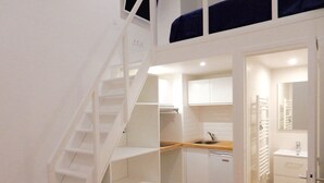 A compact kitchen with white cabinets, a wooden countertop, and a built-in dishwasher.