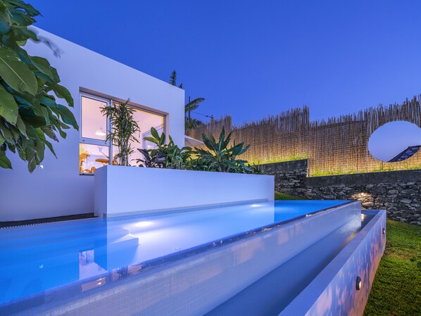 Une maison moderne dotée d’une piscine, d’un mur en pierre et d’une clôture en bois.