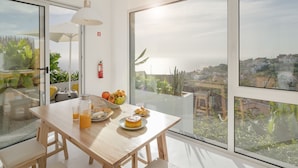 A modern dining area with a wooden table, a bowl of fruit, and a bottle of orange juice.