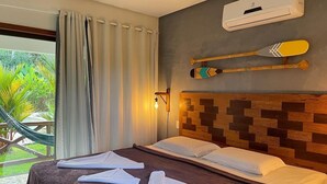 Habitación de hotel con una cama, una hamaca afuera de la ventana y un aire acondicionado instalado en la pared.