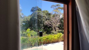 Una ventana con vista a una playa y vegetación exuberante.