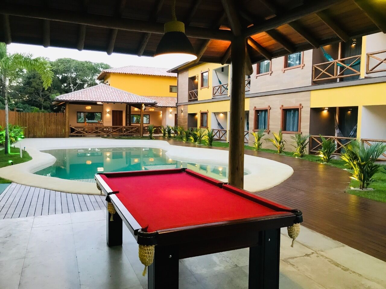 A pool table in an outdoor area with a pool and a building in the background.