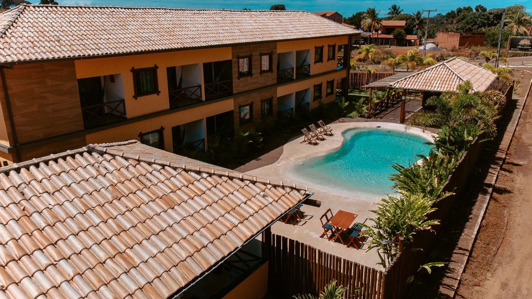 Ett semesterhotell med en swimmingpool, flera byggnader och utsikt över havet.