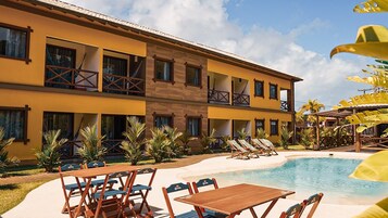 Un hotel con piscina, zona de estar al aire libre y jardín tropical.
