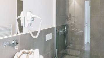 Un baño moderno con ducha envuelta en vidrio, lavamanos blanco y retrete.