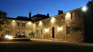 Un edificio de piedra con múltiples ventanas y una entrada bien iluminada.