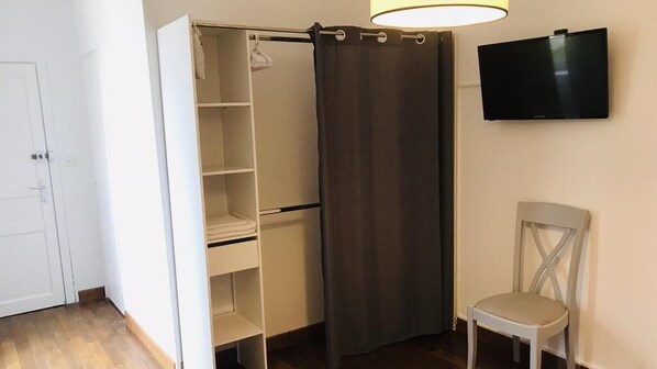Habitación con vestidor, una silla y televisión en la pared.