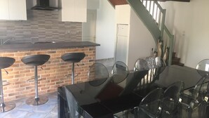 Una cocina moderna con salpicadero de ladrillo, encimera negra y mesa de comedor de vidrio con sillas.