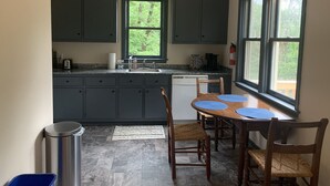 A kitchen with dark cabinets, a window, a sink, and a dining table with chairs. - Pete's Place: Forest retreat near wineries, Blue Ridge School, and Shenandoah NP (Stanardsville)