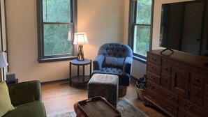 A living room with a blue armchair, a wooden cabinet, and a television. - Pete's Place: Forest retreat near wineries, Blue Ridge School, and Shenandoah NP (Stanardsville)