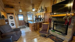 A cozy cabin interior with a fireplace, wooden floors, a dining area, and a kitchen. - 2 bed Log Cabin, w/2 Jacuzzi, 1 mi to SDC, pool, nature trails, private lake (Reeds Spring)
