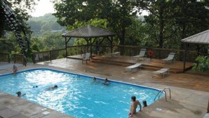 A swimming pool with people in it, surrounded by a deck with lounge chairs and a gazebo. - 2 bed Log Cabin, w/2 Jacuzzi, 1 mi to SDC, pool, nature trails, private lake (Reeds Spring)