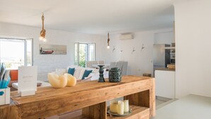 Una sala de estar moderna con una mesa de centro de madera, un sofá con cojines y una mesa de comedor con sillas.