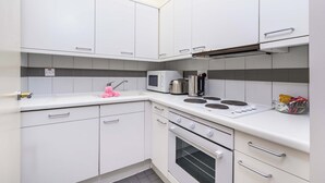 Une cuisine moderne avec des meubles blancs, un four à micro-ondes, une cuisinière et un four.