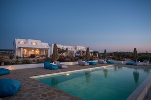 Una villa moderna con piscina, area relax esterna e giardino curato.