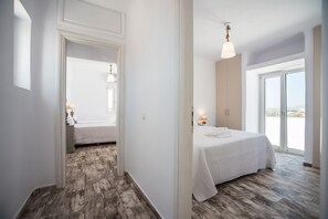 A modern bedroom with a large bed, a walk-in closet, and a sliding glass door leading to a balcony.