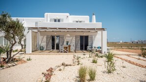 A modern white house with a covered patio, outdoor seating, and a view of the surrounding landscape. - White Sands Smile  · Fabulous pool villa, steps fr (Xifara)