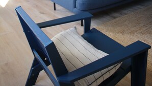Um espaço de estar moderno com um sofá azul, uma mesa de jantar de madeira e uma escada que dá para um andar superior.