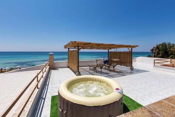 Ein Whirlpool mit Meerblick, eine Holz-Pergola und Sitzgelegenheiten im Freien.