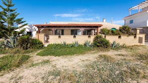 A modern house with a covered patio, surrounded by desert vegetation and a clear blue sky. - 1720 Casa Jonica by BarbarHouse (San Pietro in Bevagna)