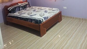 A bedroom with a bed, a ceiling fan, and two windows with curtains. - Private Executive Apartments (Accra)