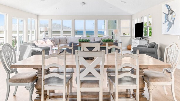 A spacious living room with a large wooden dining table surrounded by chairs, a sofa set, and a television. - Sea Gem: Beach/Slp 10 Adults plus children/Amenities (St. Augustine)