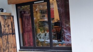 Houten vloer die leidt naar een glazen schuifdeur met uitzicht op een besneeuwde omgeving.