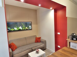 A modern living room with a sofa, a small table, and a fish tank on the wall.