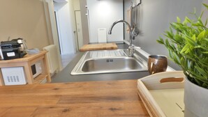 A modern kitchen with a stainless steel sink, wooden countertop, and a coffee machine. - Charming House in Old Town Desenzano (Desenzano del Garda)