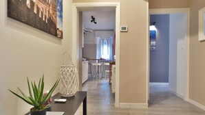 A hallway with a potted plant, a white decorative lamp, and a painting on the wall. - Charming House in Old Town Desenzano (Desenzano del Garda)
