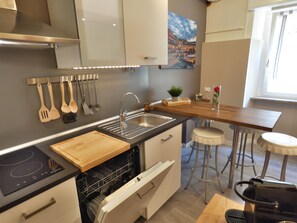 A modern kitchen with a built-in dishwasher, a wooden countertop, and a stainless steel sink.