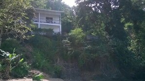 A building with a balcony, surrounded by dense vegetation and a sandy area near a body of water. - Tranquil and Peaceful Parlatuvier (Parlatuvier)