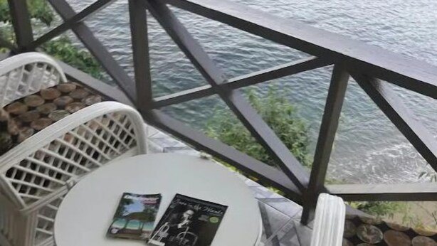 A small outdoor seating area with a round table and two white wicker chairs, overlooking a body of water. - Tranquil and Peaceful Parlatuvier (Parlatuvier)