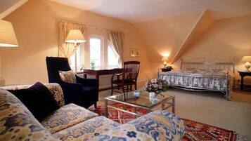 A cozy bedroom with a bed, a sofa, a chair, and a small table.