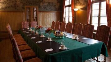 A conference room with a long table set for a meeting, surrounded by upholstered chairs.