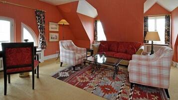 A cozy living room with a red sofa, two plaid armchairs, a coffee table, and a patterned rug.