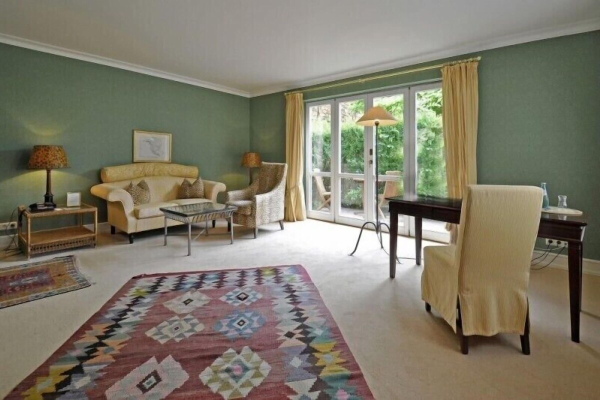 A living room with a sofa, armchair, coffee table, and a patterned rug.