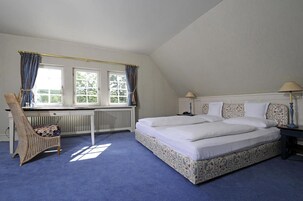 Un dormitorio con una cama grande, una silla y una ventana con cortinas.
