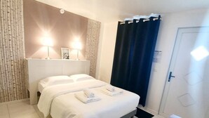 Een hotelkamer met een bed, twee bedlampen, een houten vloer en een deur.