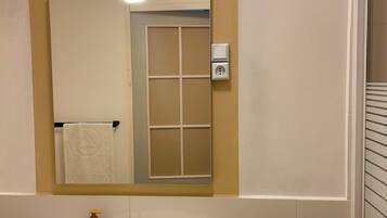 Un baño con un lavabo blanco, un espejo de arco superior y una toalla colgada en la pared.