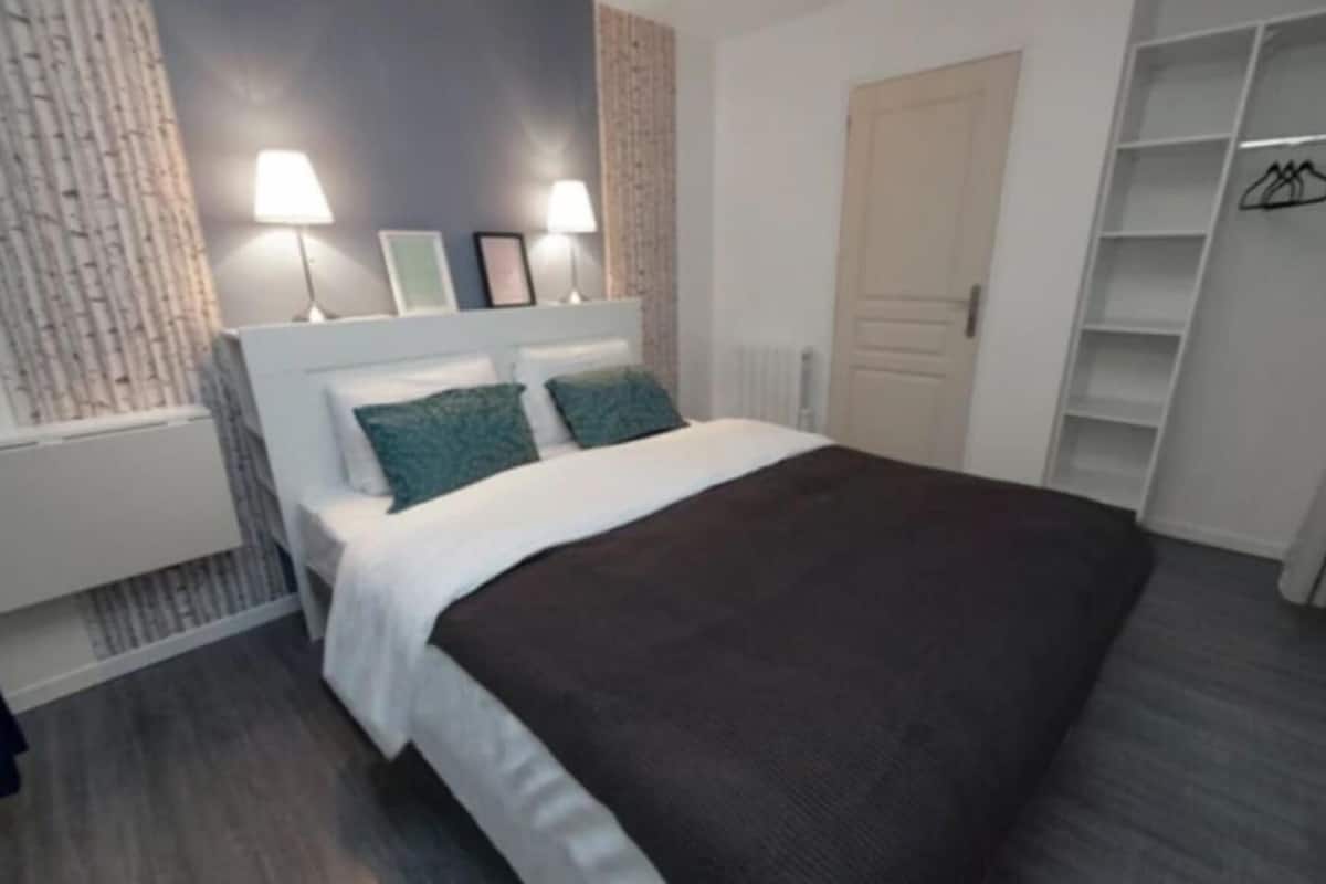 Une chambre à coucher avec un lit, des lampes de chevet, une armoire et un radiateur.