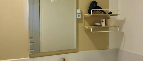 A bathroom with a white sink, a toilet, a mirror, and a towel hanging on the sink.